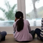 Enfants qui regardent par la fenêtre pendant une tempête