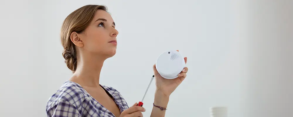 Femme qui installe un détecteur de fumée